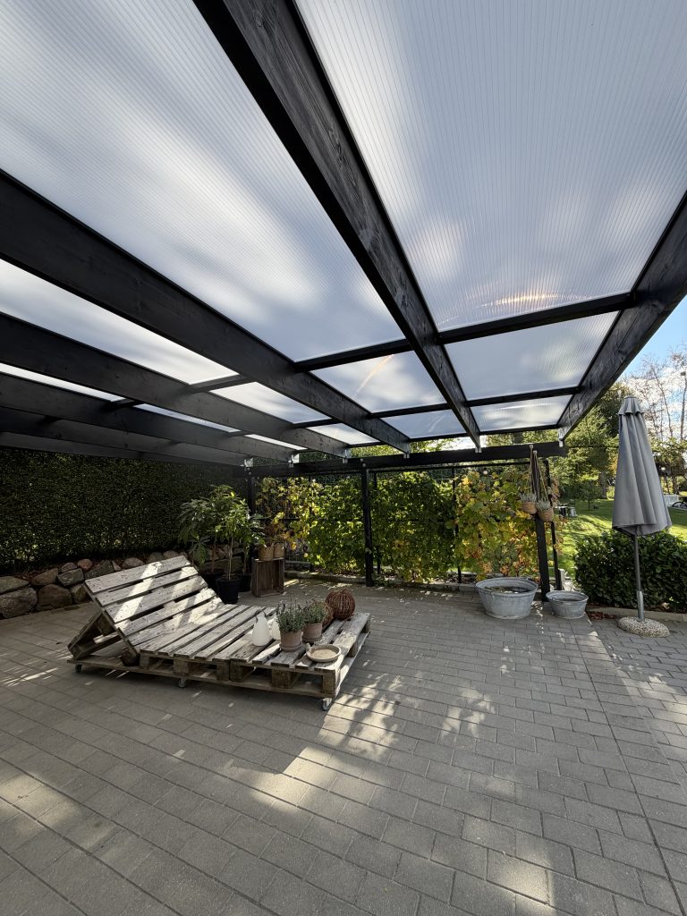 En overd&aelig;kket terrasse med termotag og sorte profiler fra Holmegaard Plast